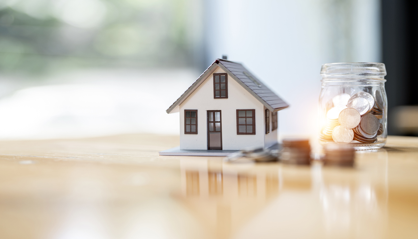 Real estate, property and financial concept. House model and stack of coins on the table for background.