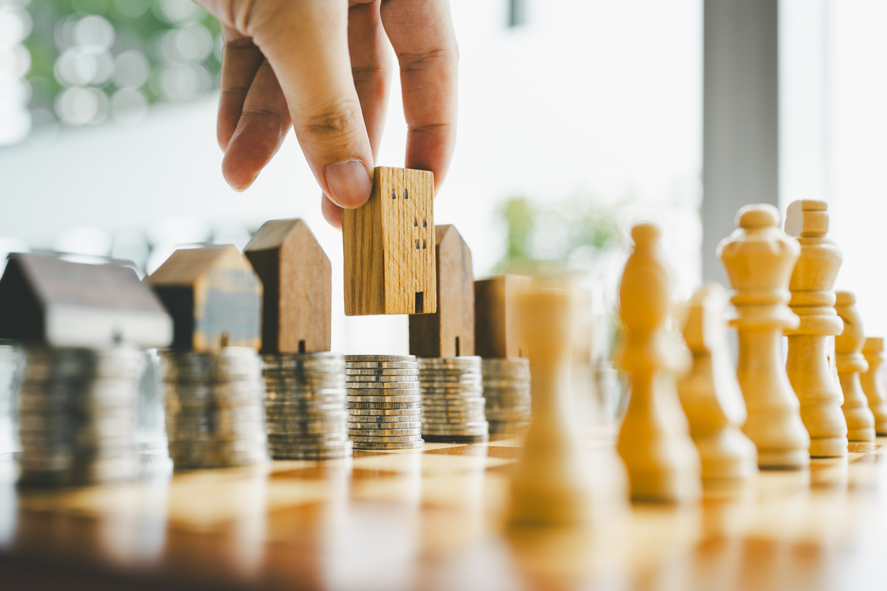 Chess, stack of coins and house models in chess game, competition success play. strategy, management or leadership concept